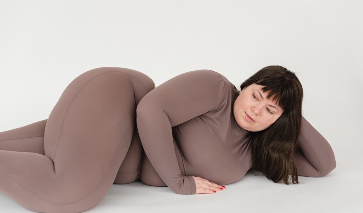 High angle of serious plus size female with long hair leaning on hand while lying against white background