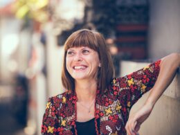 woman in floral-themed cardigan leaning on fence in bokeh photography